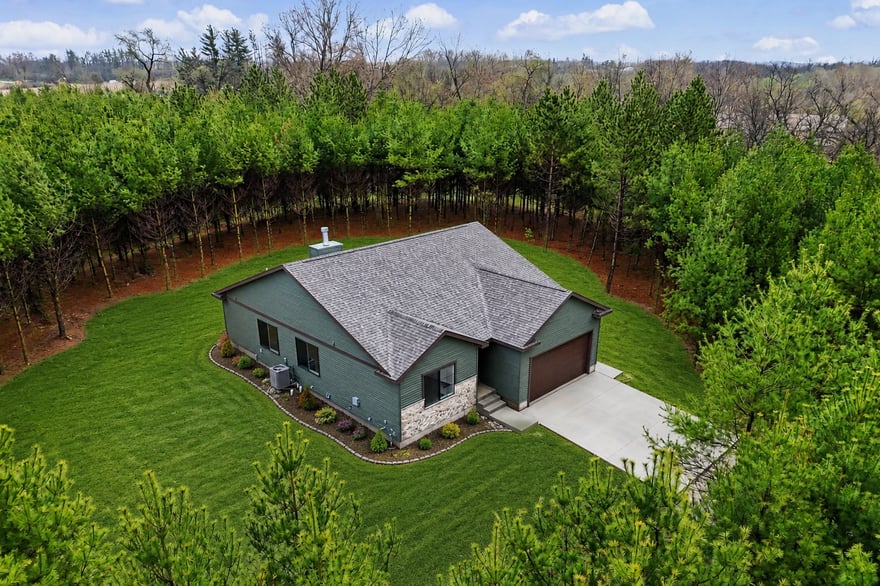 Completed custom home surrounded by mature evergreen trees on a former Christmas tree farm in rural Iowa.