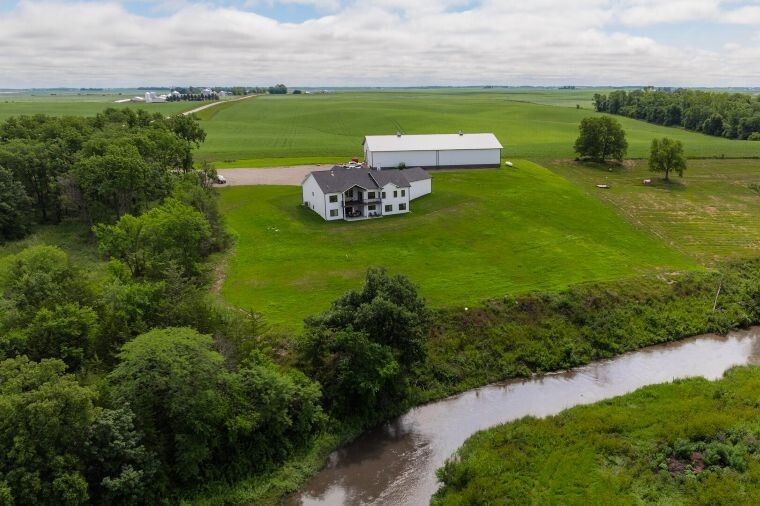 Aerial view of a rural Iowa parcel with overlays marking a future home site, driveway, and utility paths.